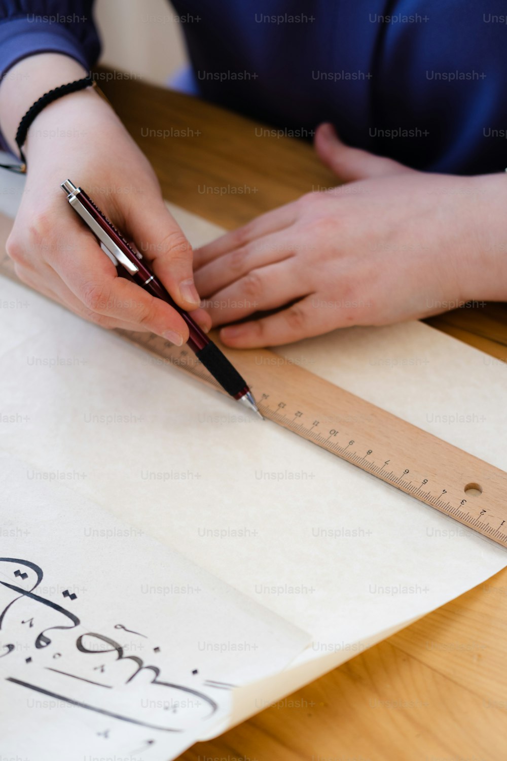 a person with a pen and ruler on a table