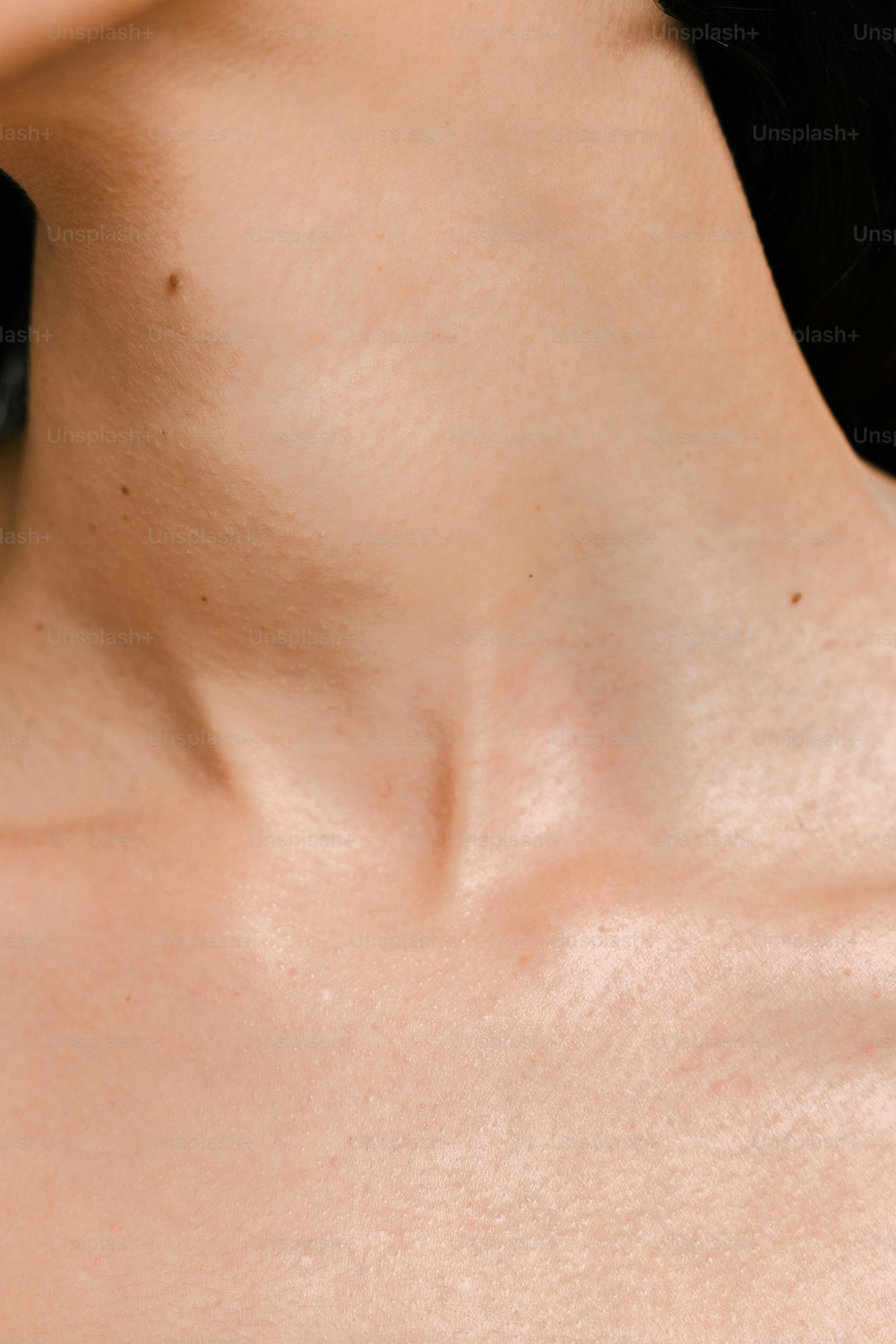 eine Nahaufnahme des Halses einer Frau mit schwarzem Hintergrund