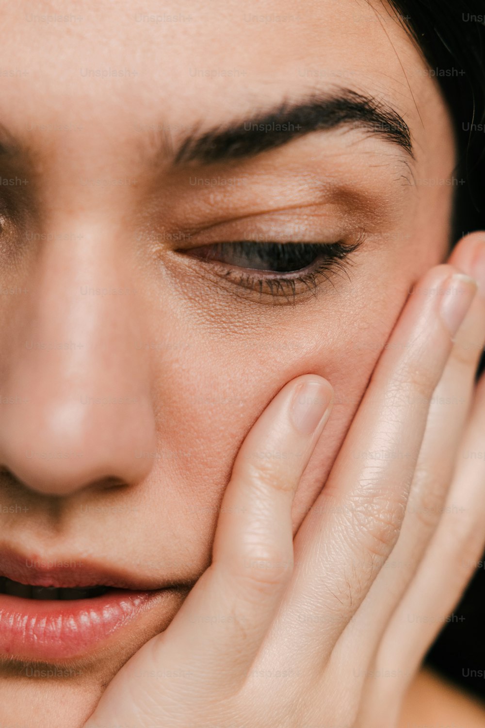 a close up of a woman holding her hand to her face