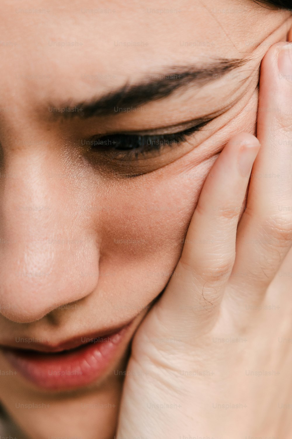 a close up of a person holding their hand to their face