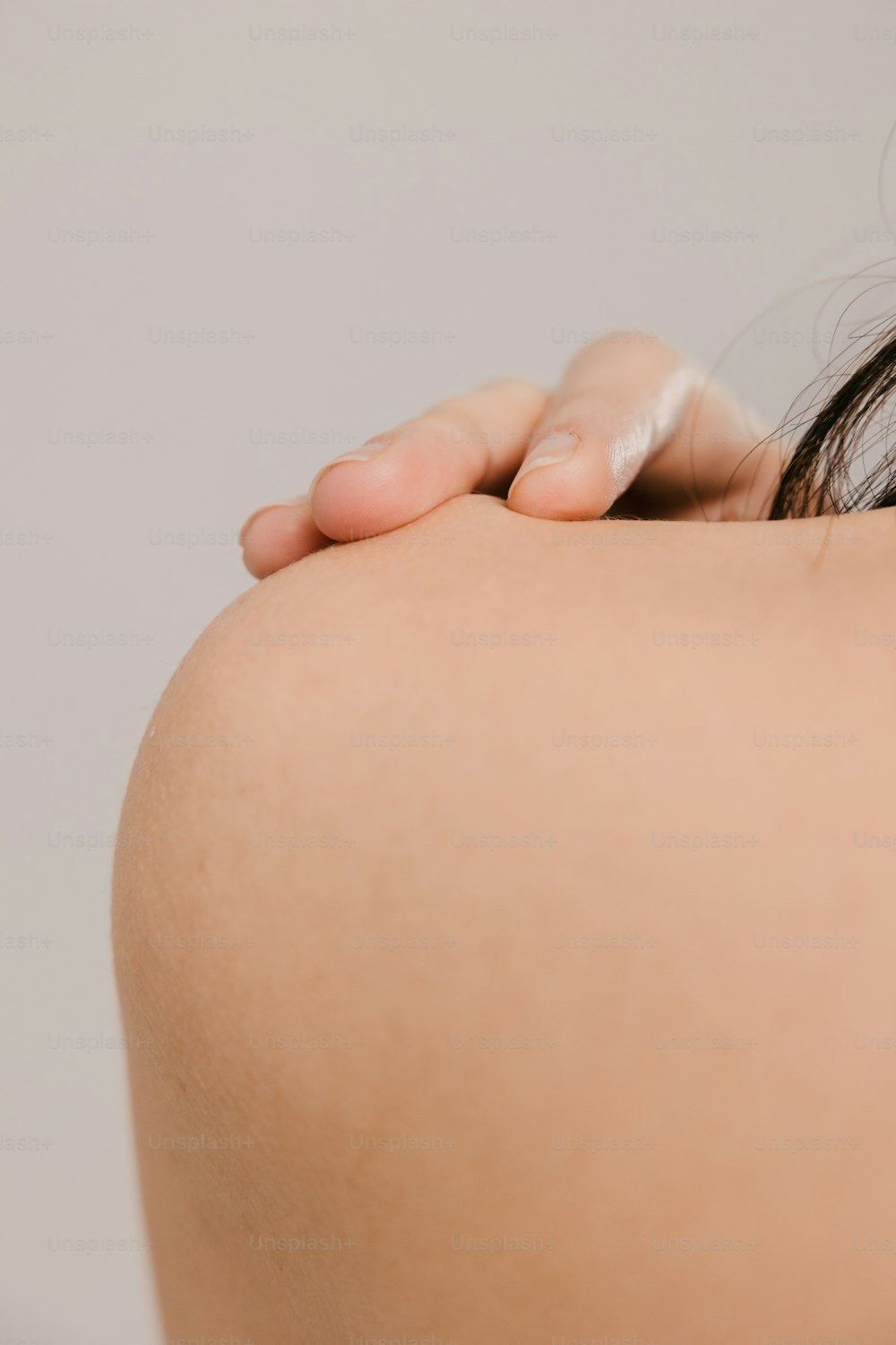 a close up of a woman's back with her hand on her shoulder