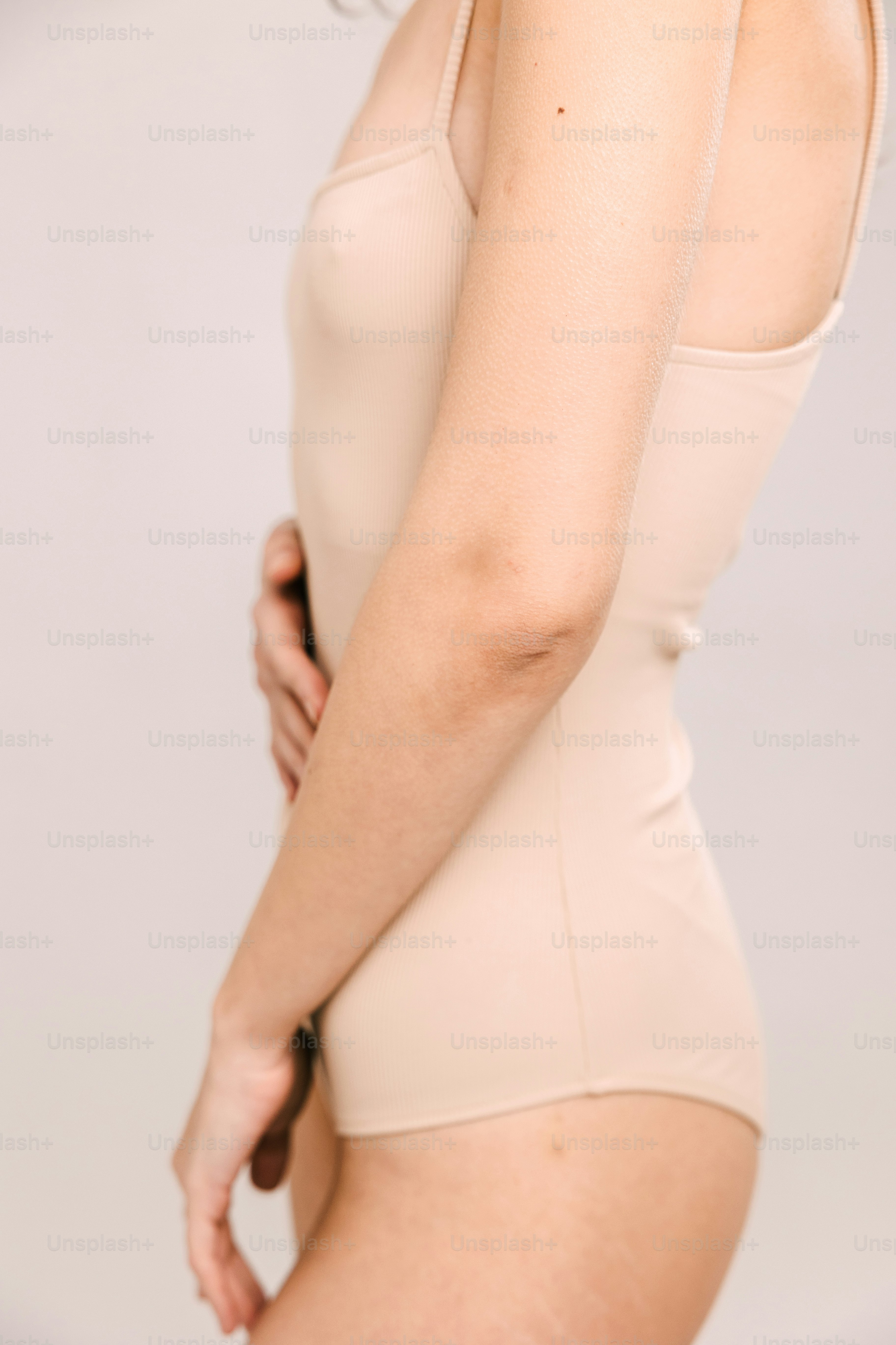 a woman in a tan bodysuit posing for a picture