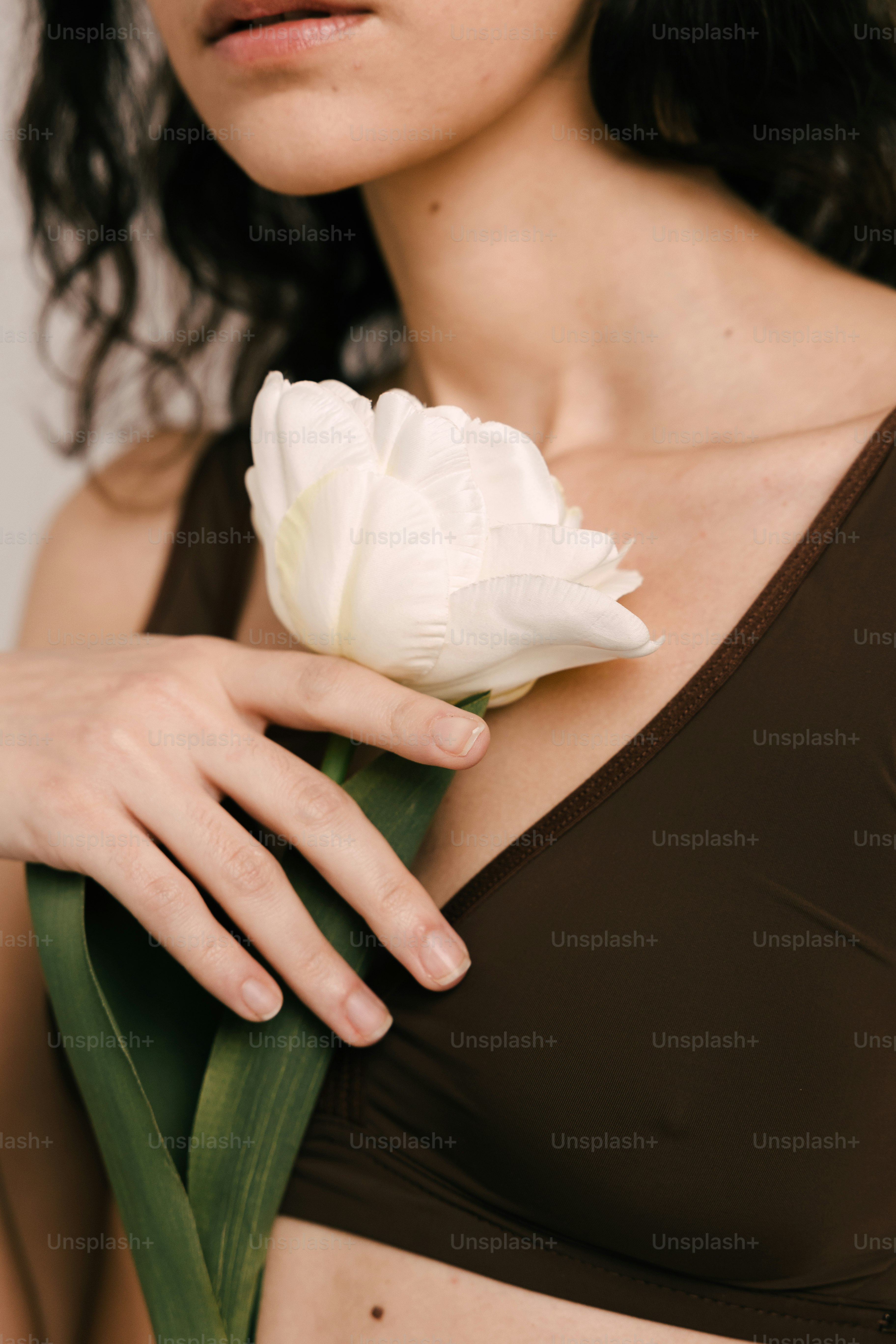 Una mujer sosteniendo una flor blanca en su mano derecha