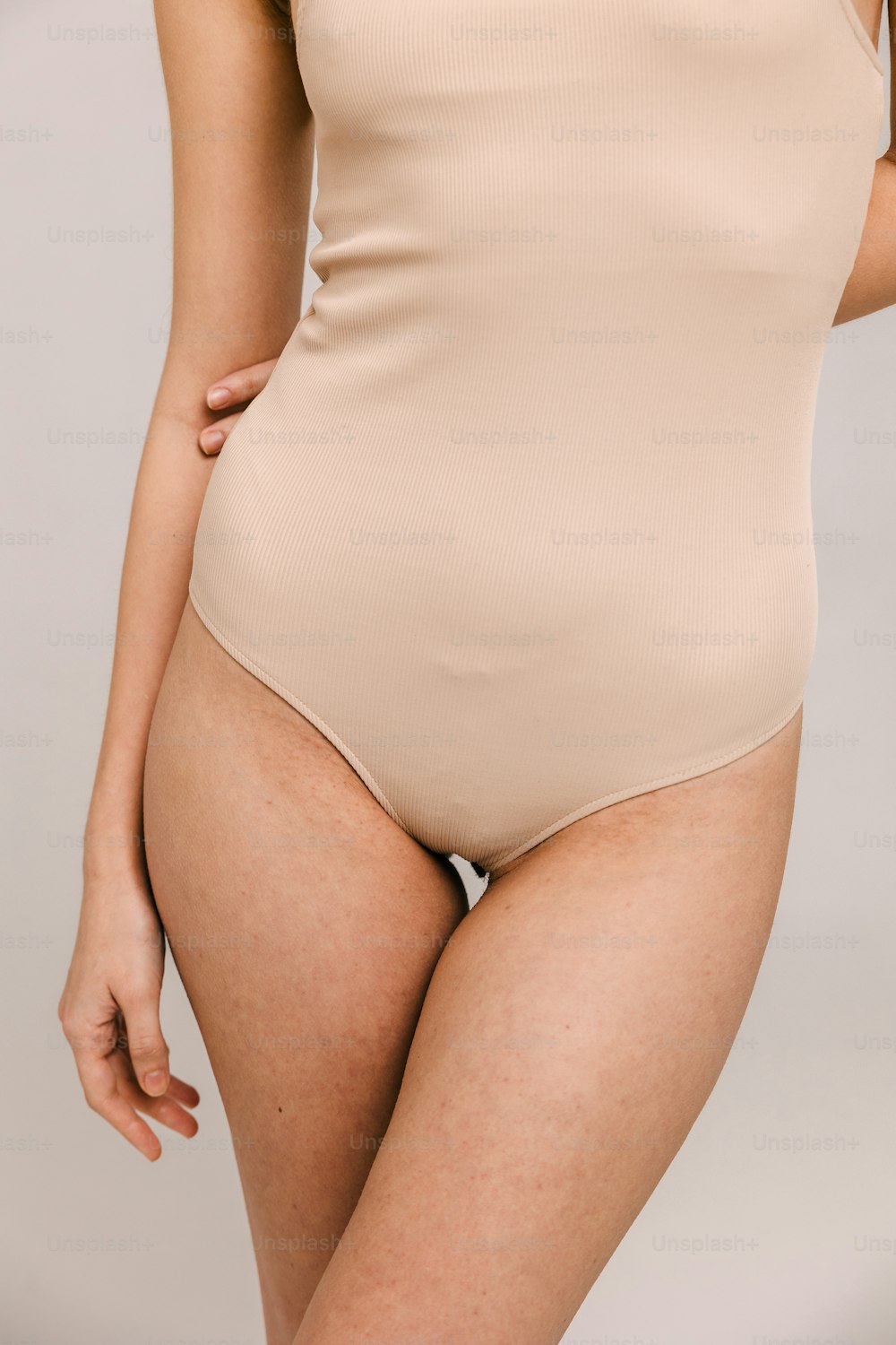 a woman in a tan bodysuit posing for the camera