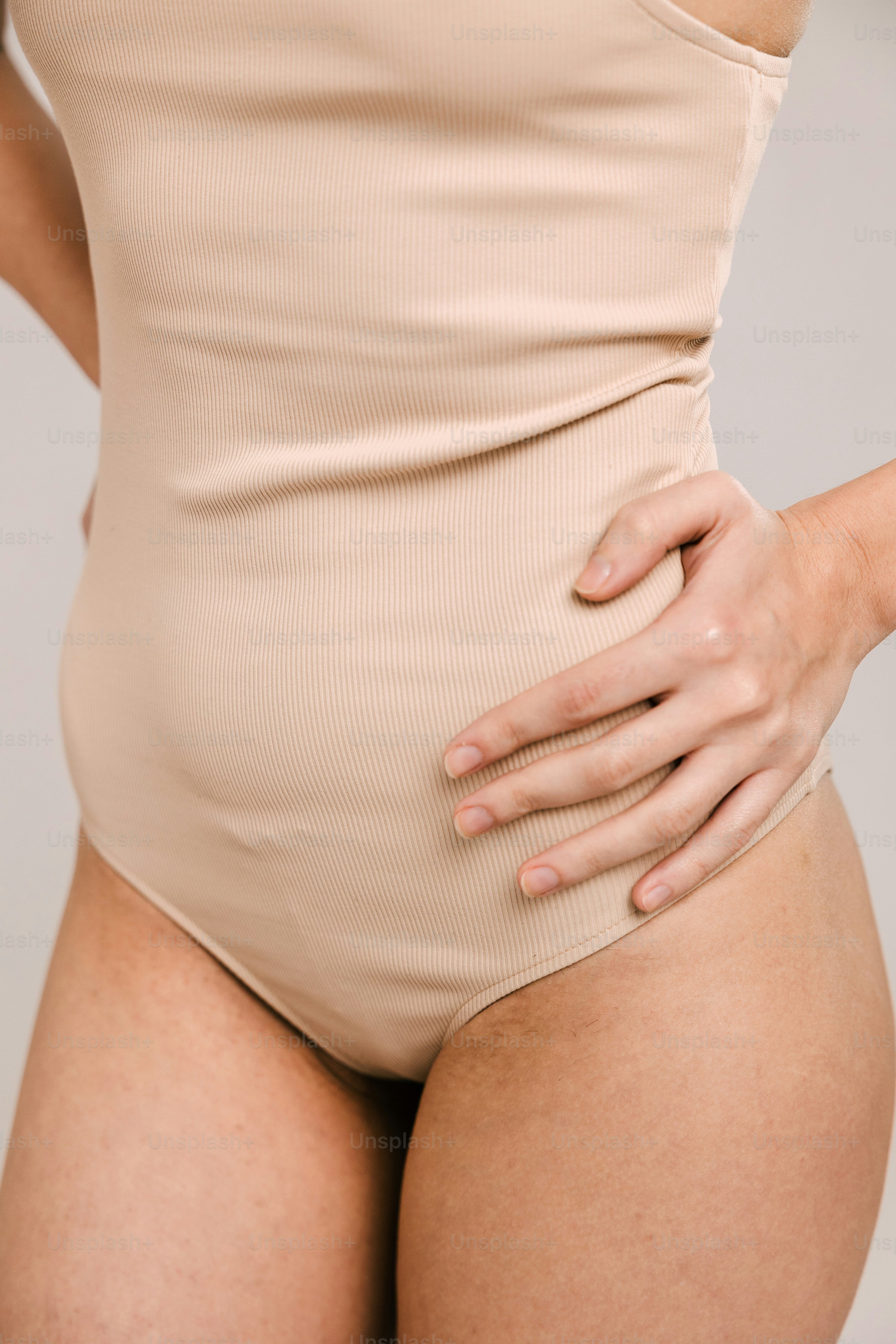 日焼けしたボディスーツを着た女性が腰に手を当てている