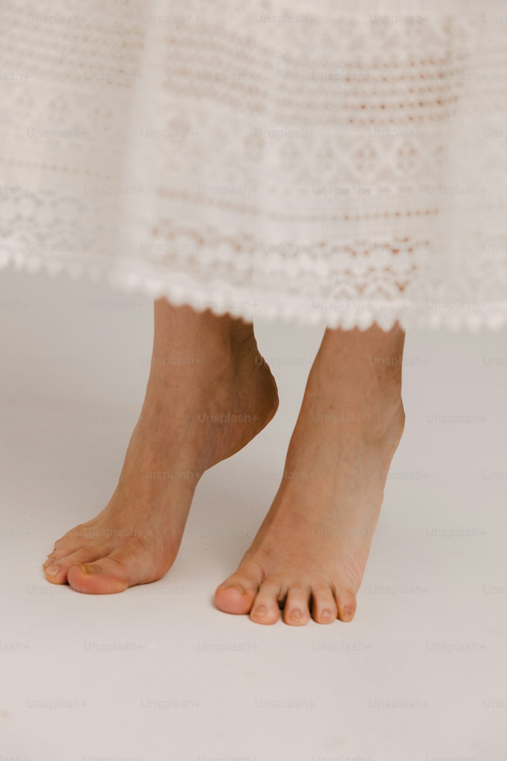 un primo piano dei piedi nudi di una persona che indossa un vestito bianco