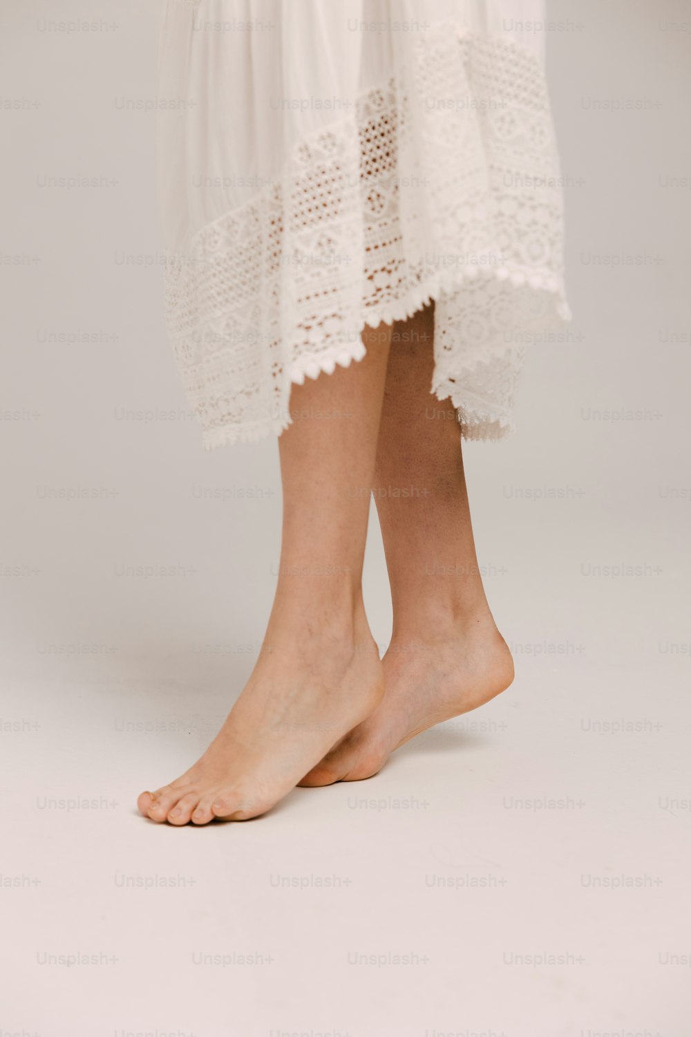 um close up das pernas de uma pessoa usando um vestido branco