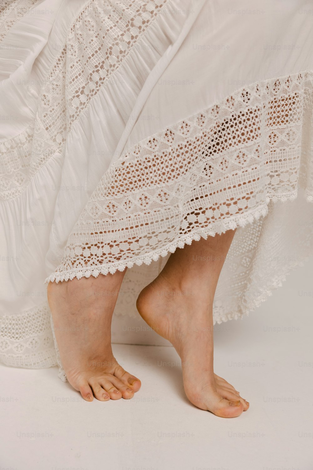 Los pies descalzos de una mujer con un vestido blanco