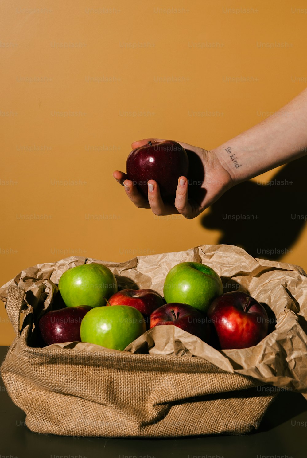 a person holding an apple in front of a basket of apples