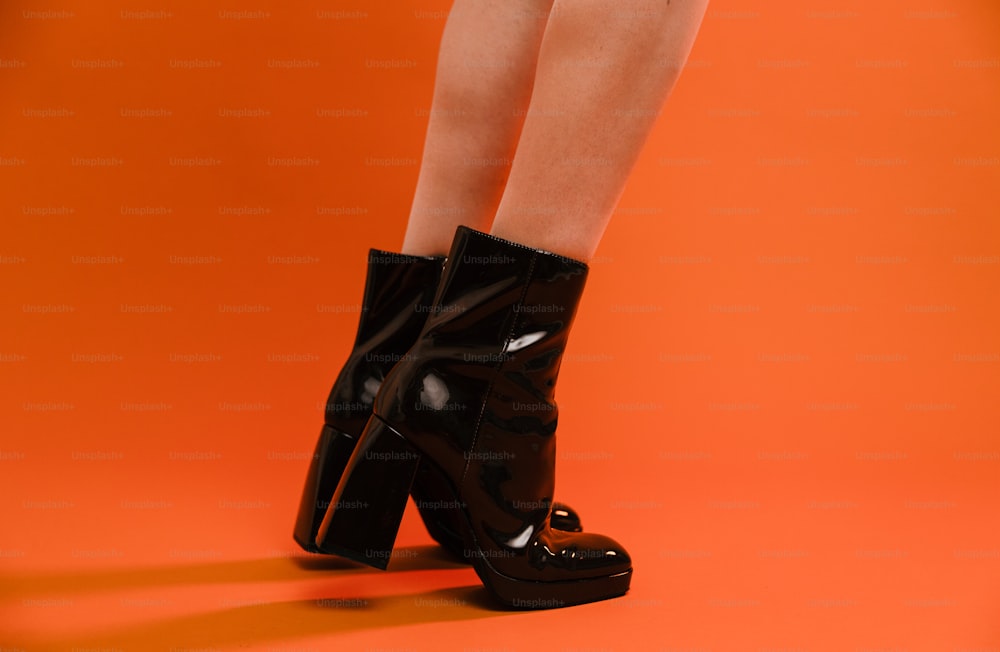 Die Beine einer Frau in schwarzen Stiefeln mit hohen Absätzen