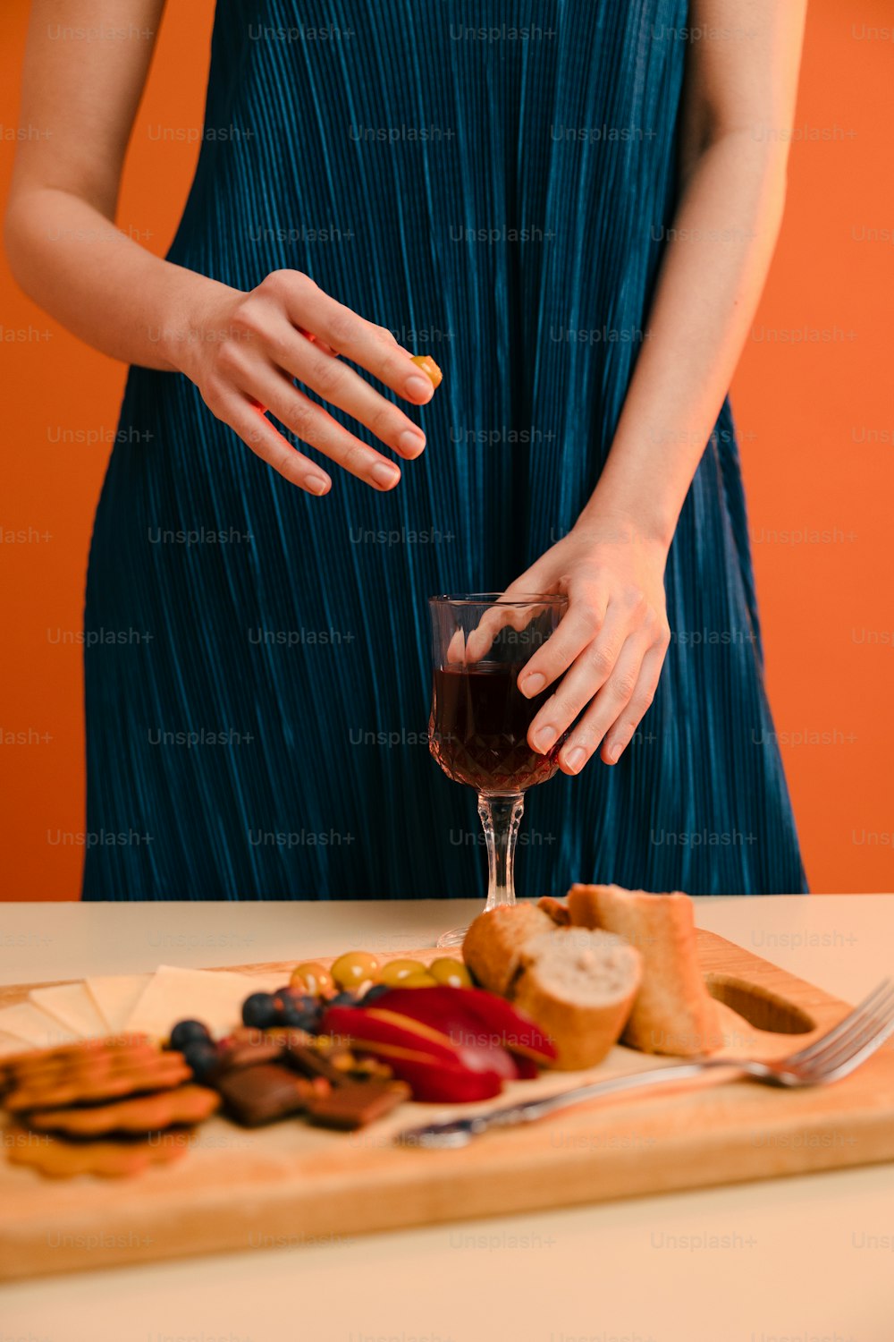 a woman holding a glass of wine in front of a plate of food