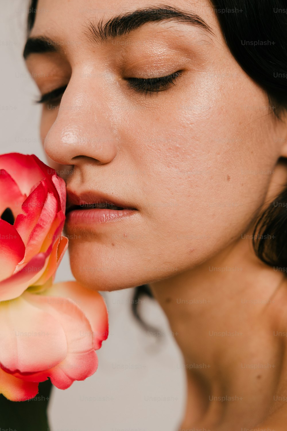 uma mulher cheirando uma flor com os olhos fechados