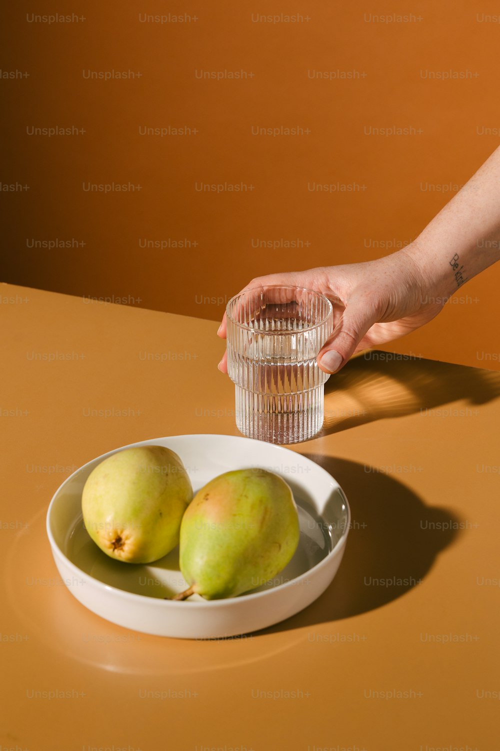 a person holding a glass next to a bowl of fruit