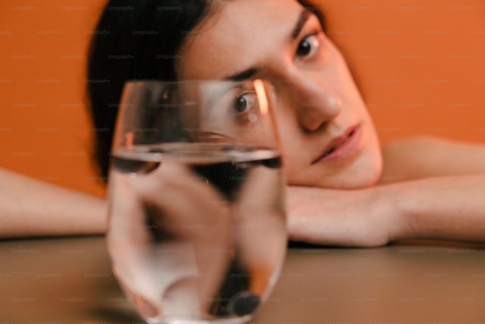 uma mulher sentada em uma mesa com um copo de vinho