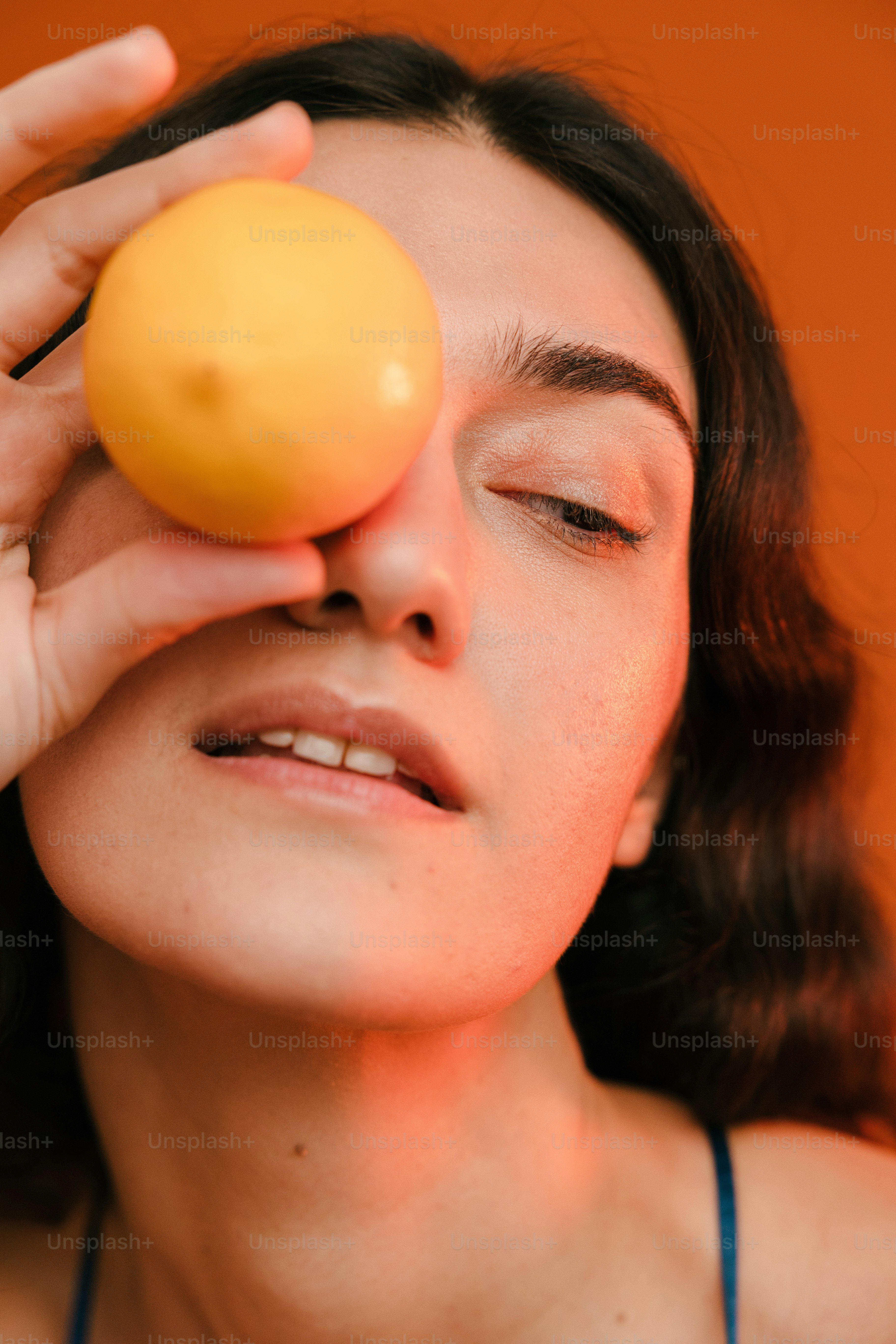 Une femme tenant une orange jusqu’à l’œil
