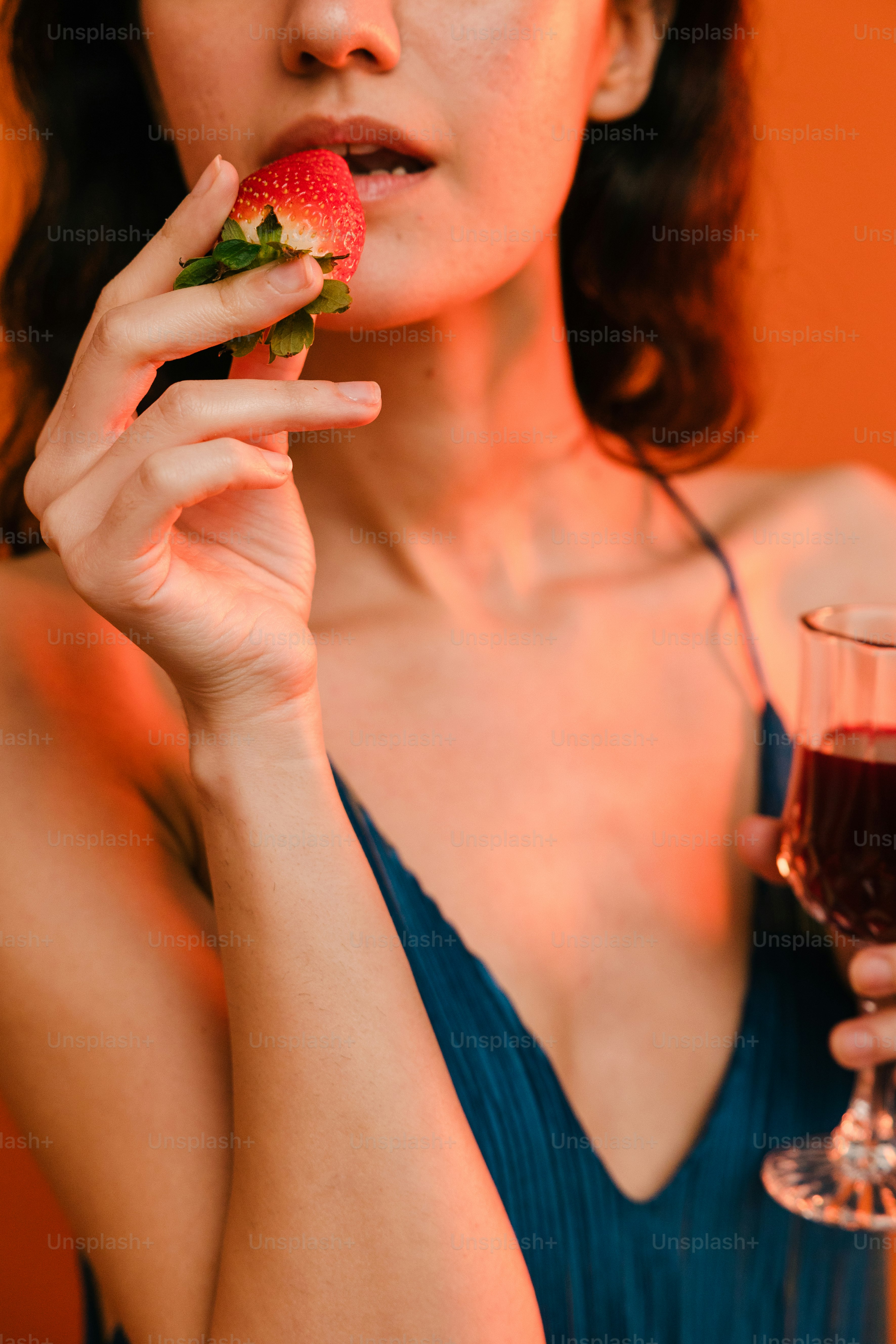 a woman holding a strawberry and a glass of wine