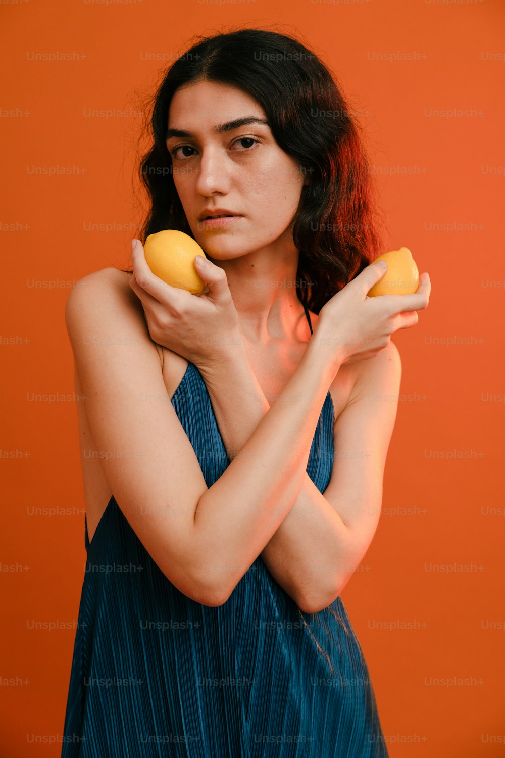 a woman in a blue dress holding two oranges