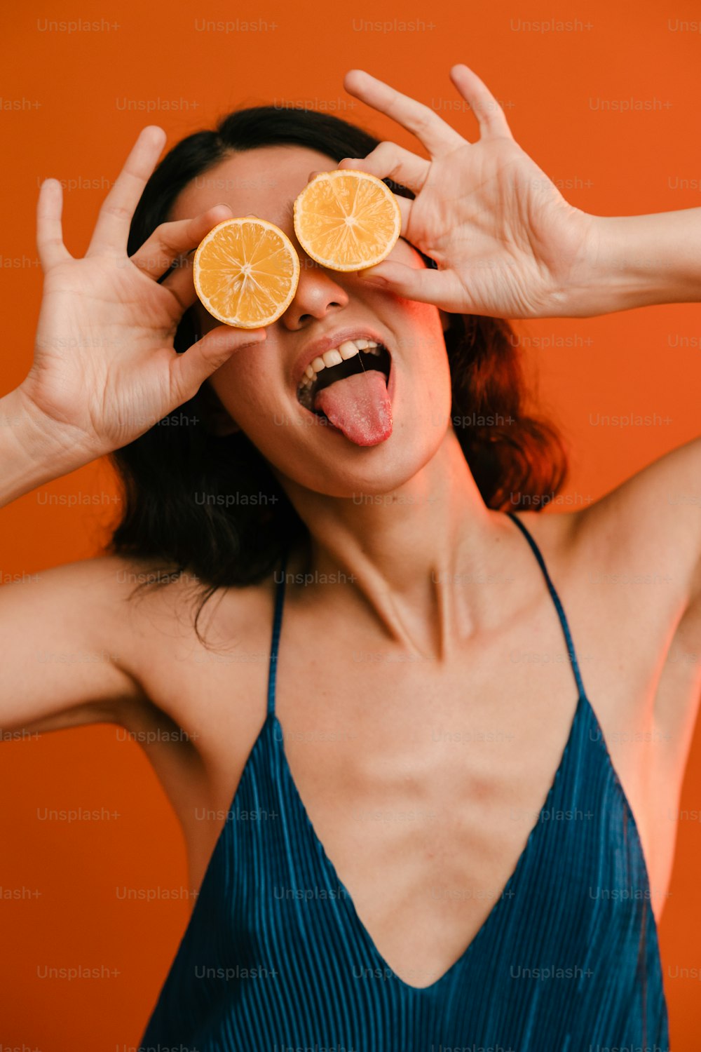 a woman holding two orange slices over her eyes