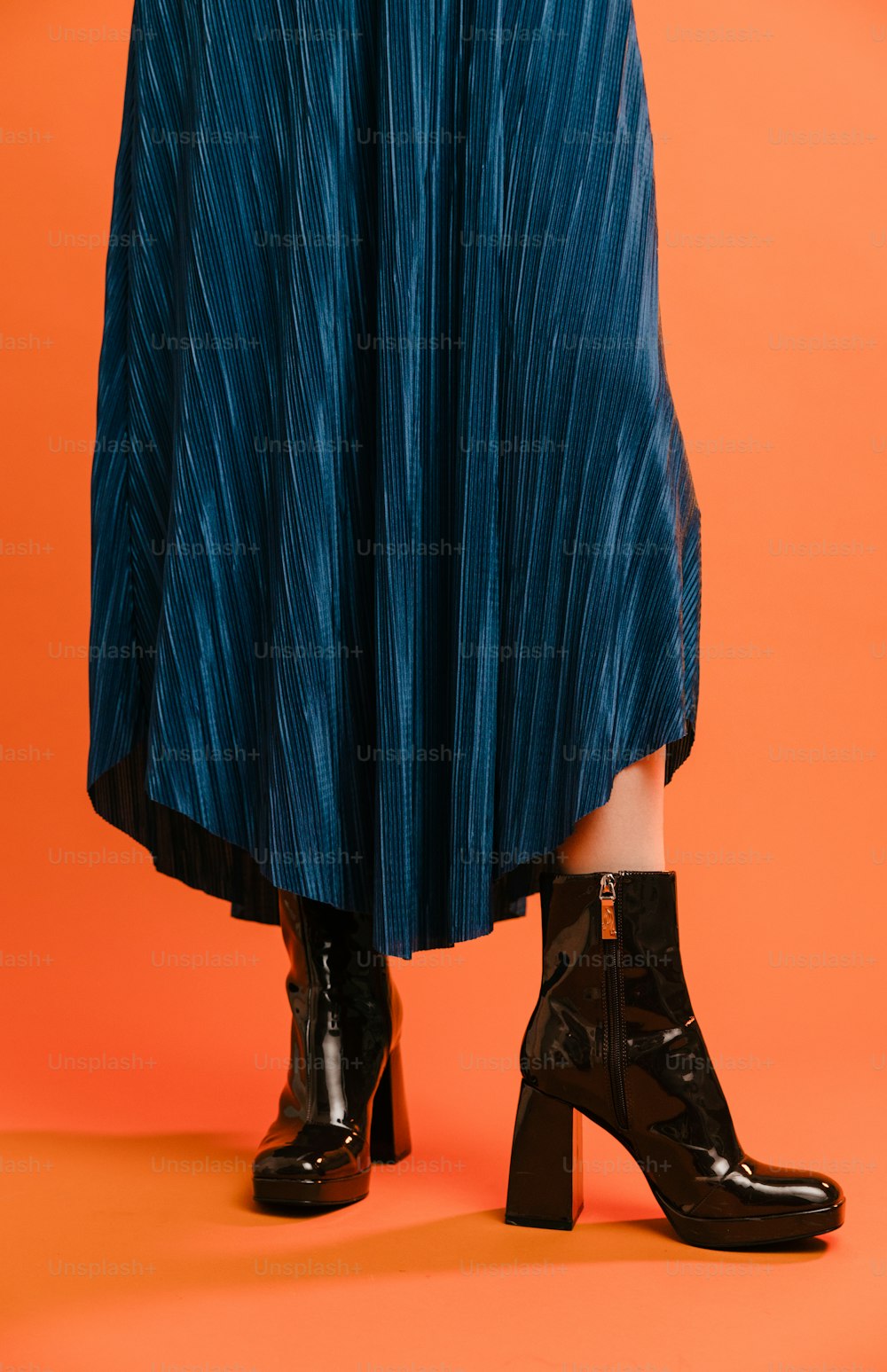 Une femme en jupe bleue et bottes noires