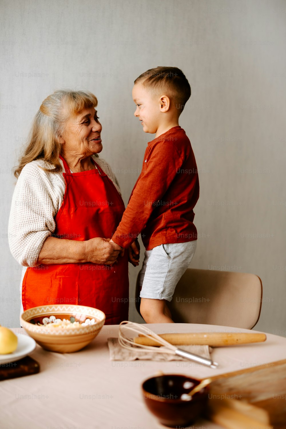 an older woman and a young boy standing at a table