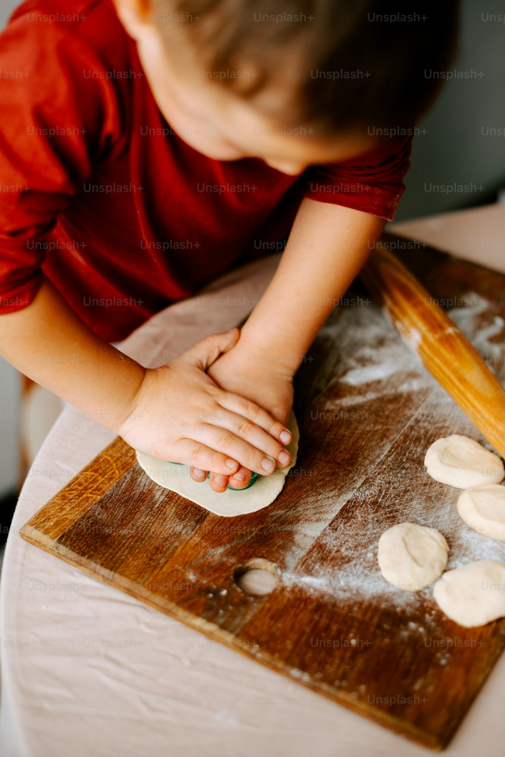 a young boy rolling dough on a wooden board