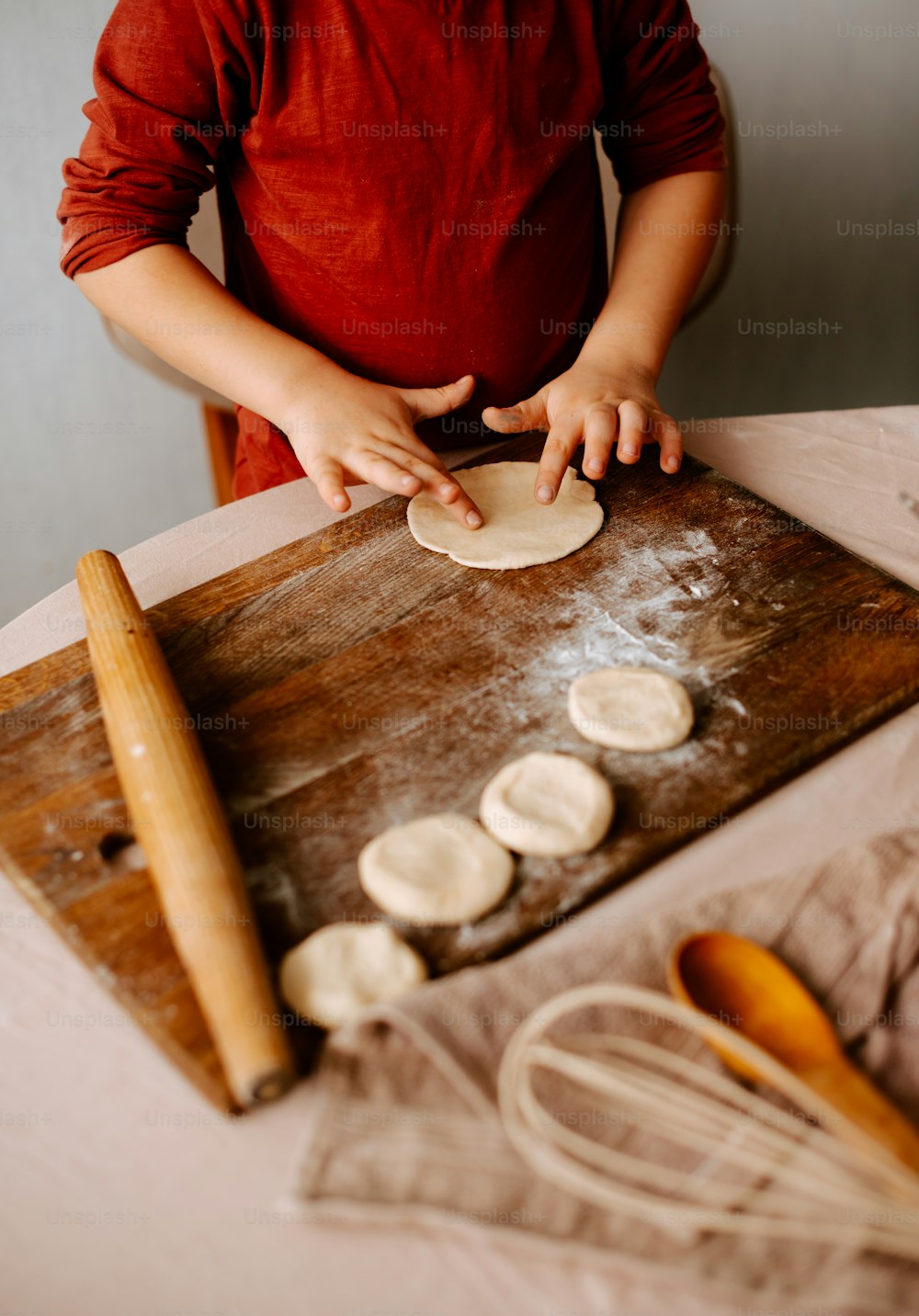 a young boy is making pizza dough on a table
