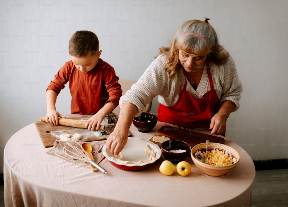 a woman and a boy are preparing food on a table