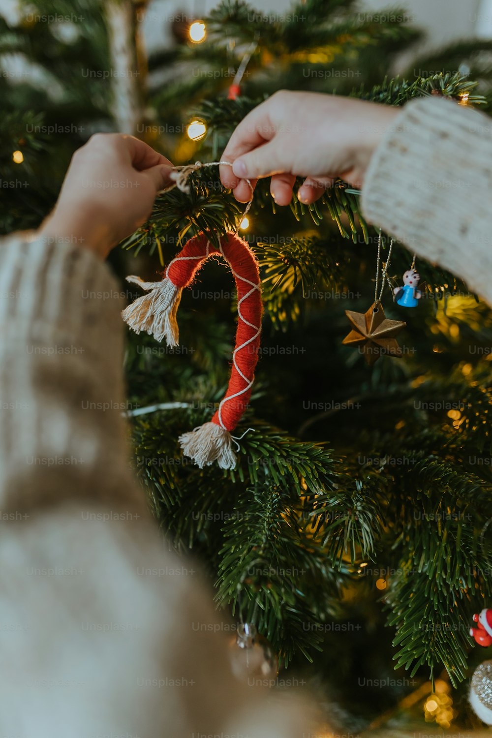 a person decorating a christmas tree with a candy cane