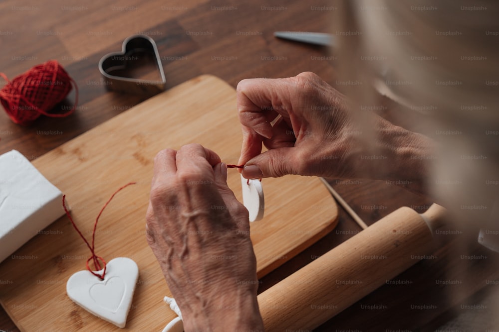 a woman is making a heart shaped ornament