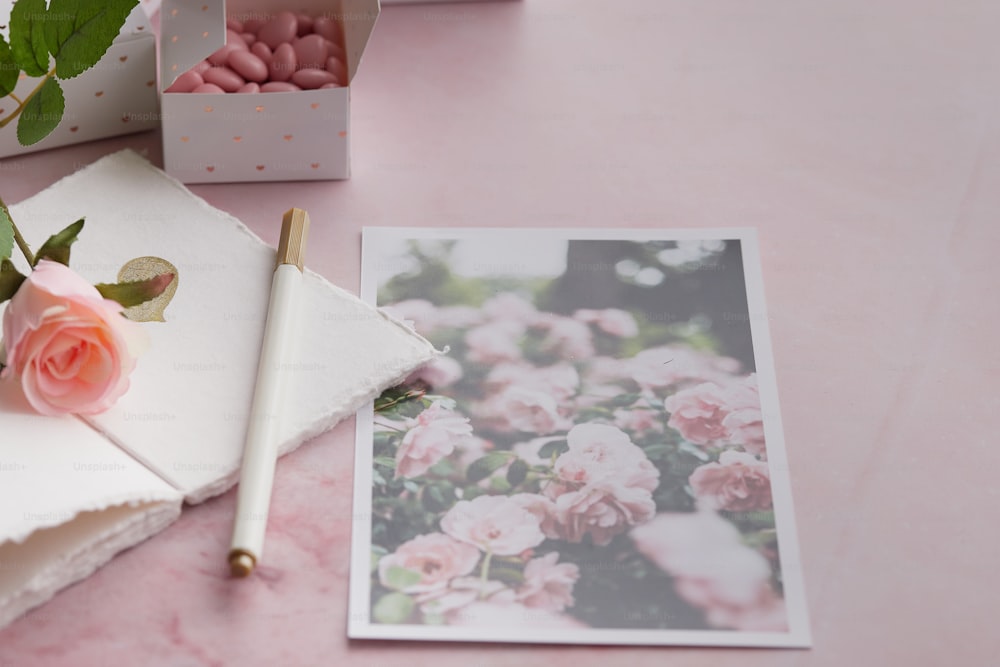 a pink table topped with pink flowers and a notepad