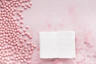 uma caixa branca com doces cor-de-rosa em uma superfície de mármore rosa