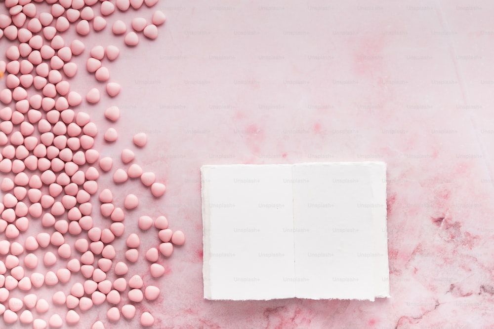 une boîte blanche avec des bonbons roses sur une surface en marbre rose