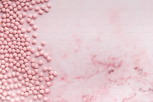 a pink marble background with pink and white candies