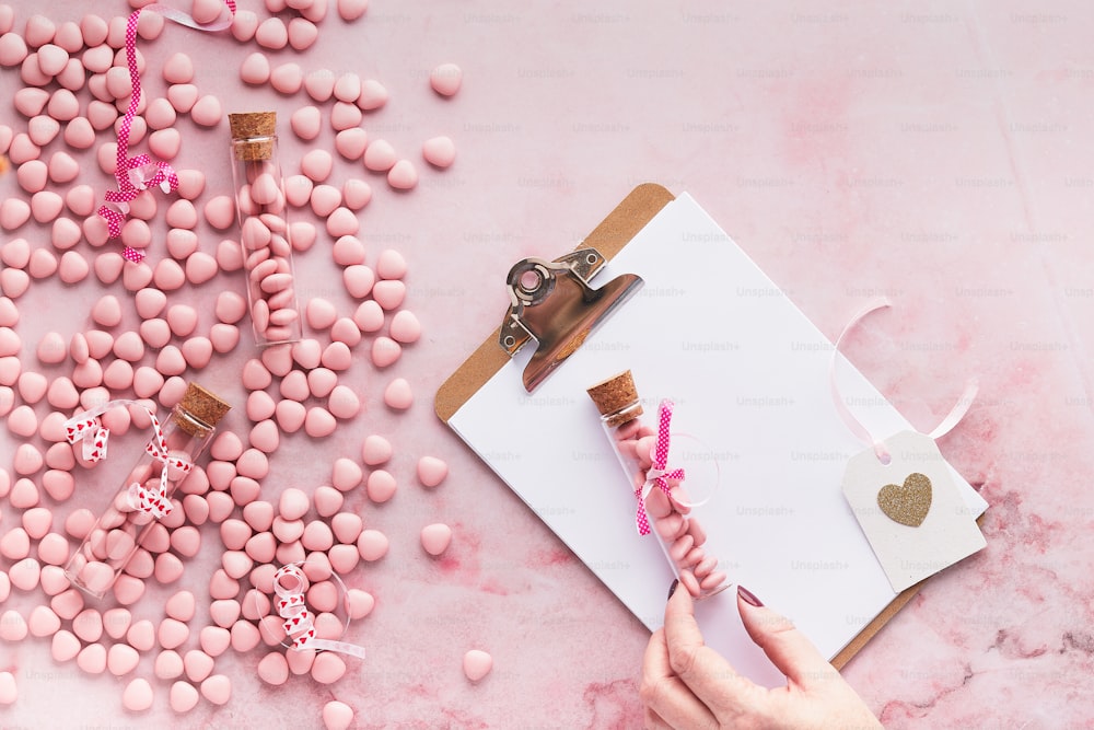 Una persona sosteniendo un par de tijeras junto a un caramelo rosa