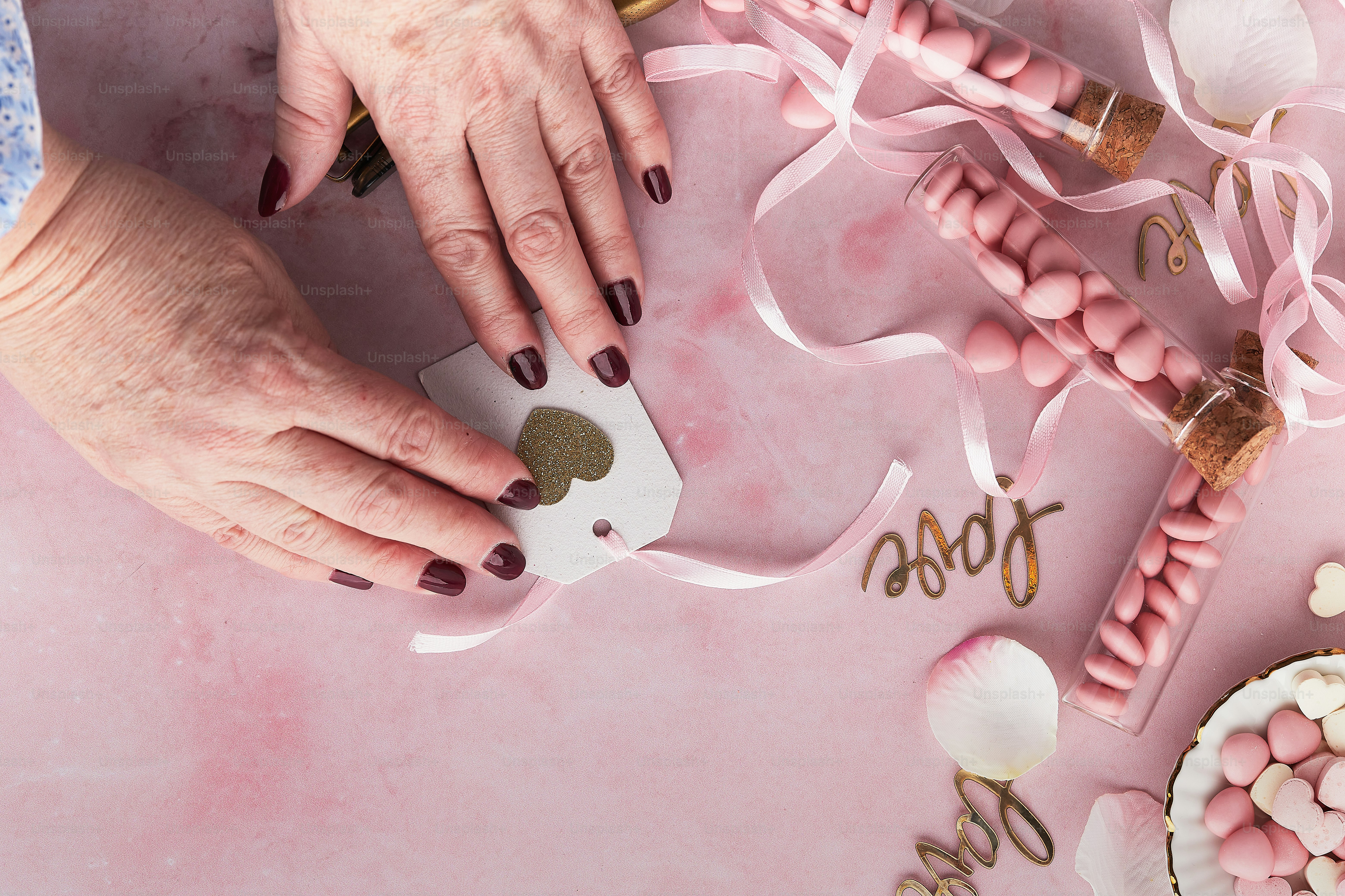 mãos de uma mulher com uma manicure em uma superfície rosa