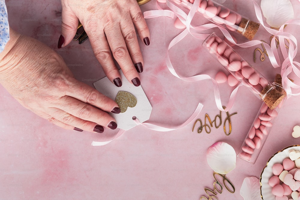 mãos de uma mulher com uma manicure em uma superfície rosa