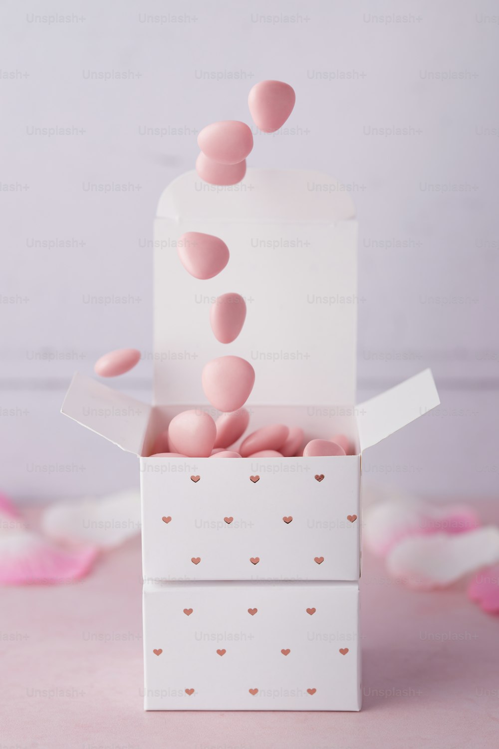 uma caixa branca cheia de corações cor-de-rosa em cima de uma mesa