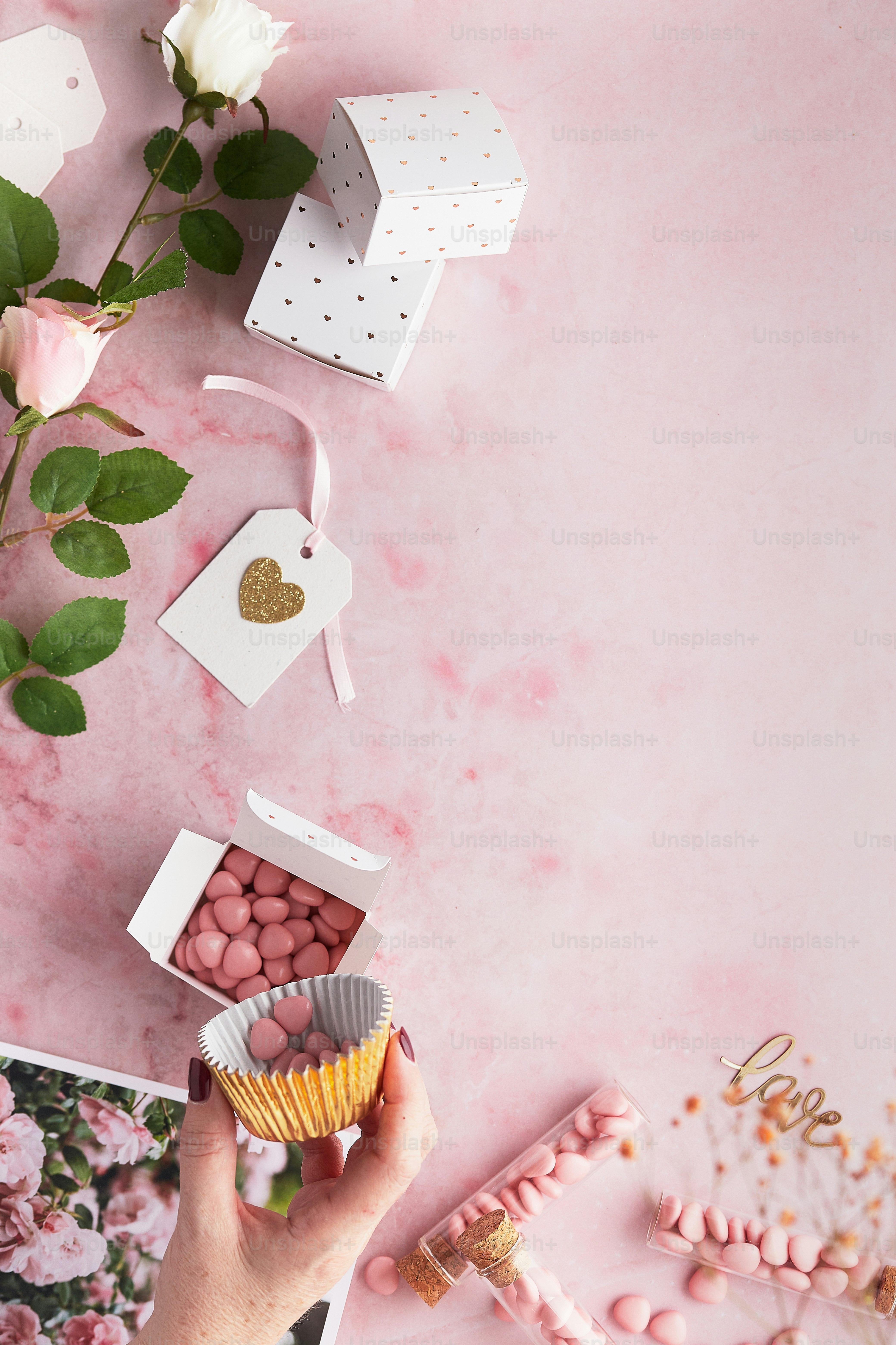 a person holding a cupcake in front of a pink background