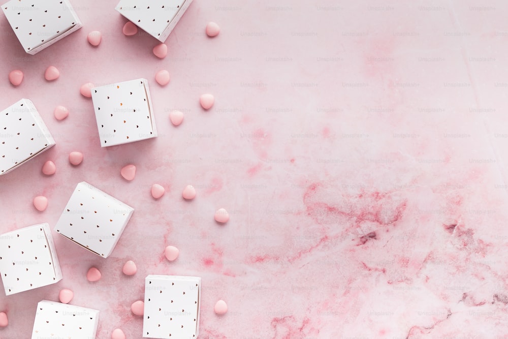 a group of white and pink candy cubes on a pink marble surface