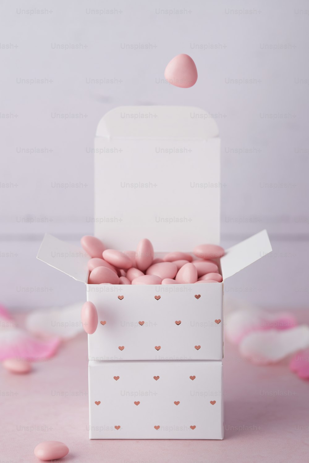una scatola bianca piena di cuori di caramelle rosa