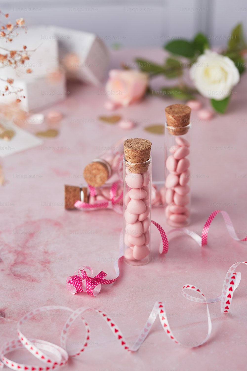 a pink table topped with two bottles filled with candy