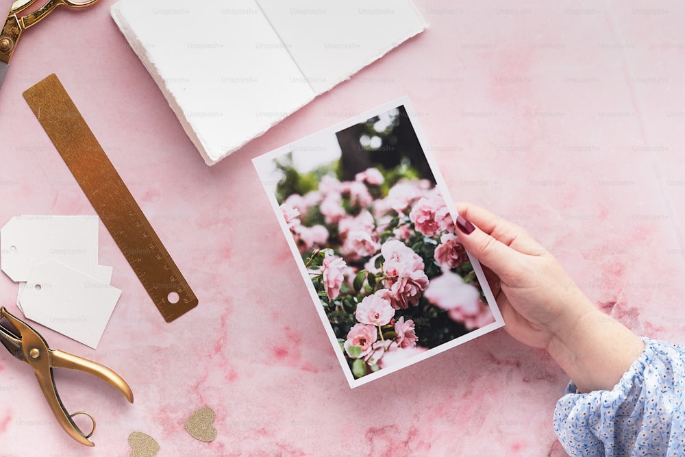 uma pessoa segurando uma foto de flores cor-de-rosa