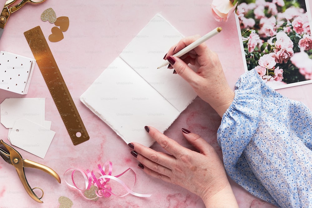 a woman's hands holding a pencil and writing on a notebook