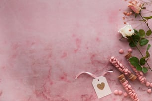 una mesa de mármol rosa con cuentas rosas y una rosa blanca