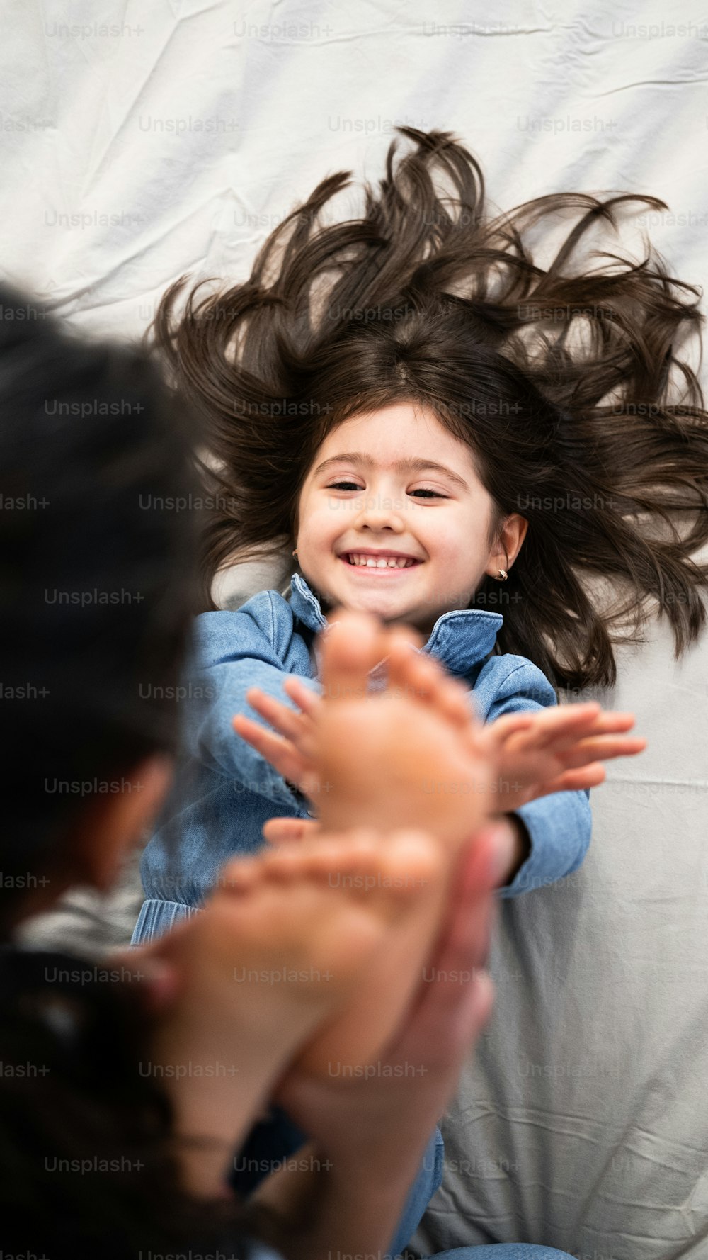a little girl laying on a bed with her hair flying in the air