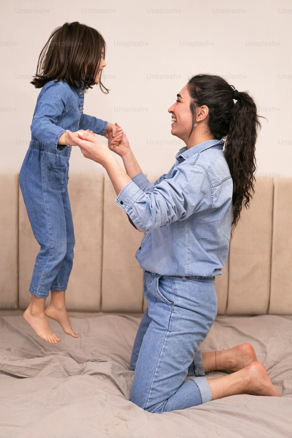 a woman is sitting on a bed playing with a child