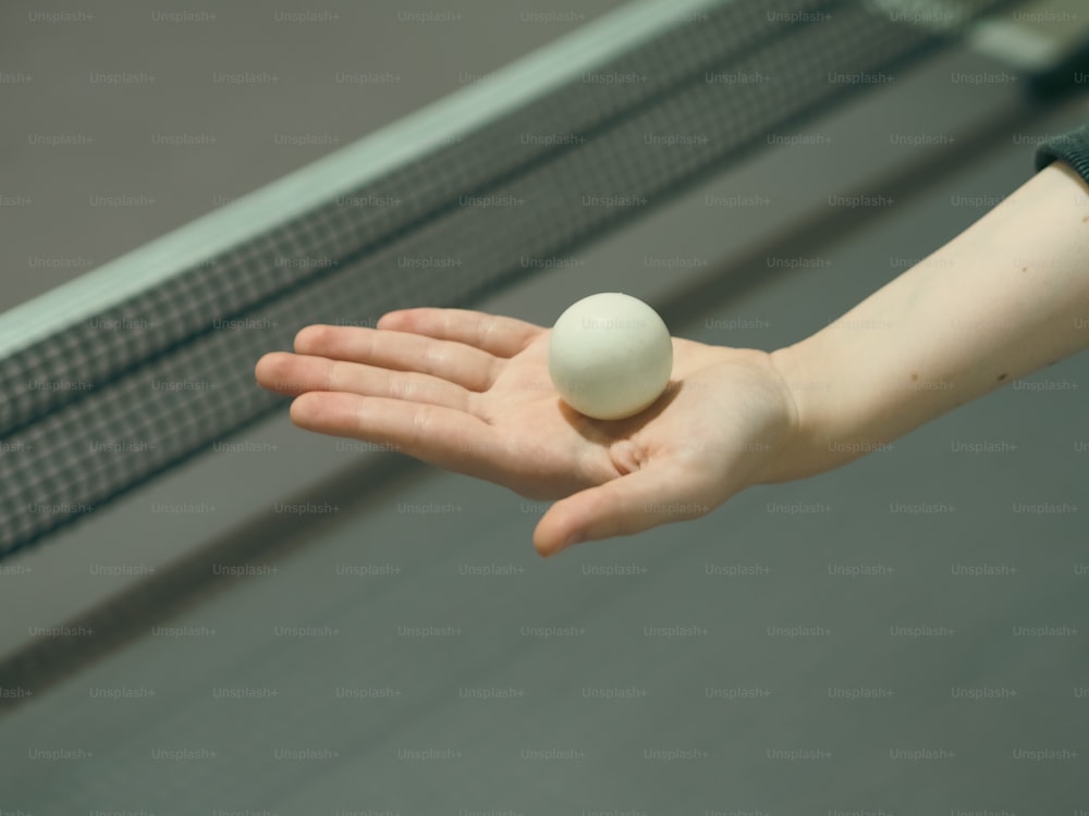 a person holding a ping pong ball in their hand