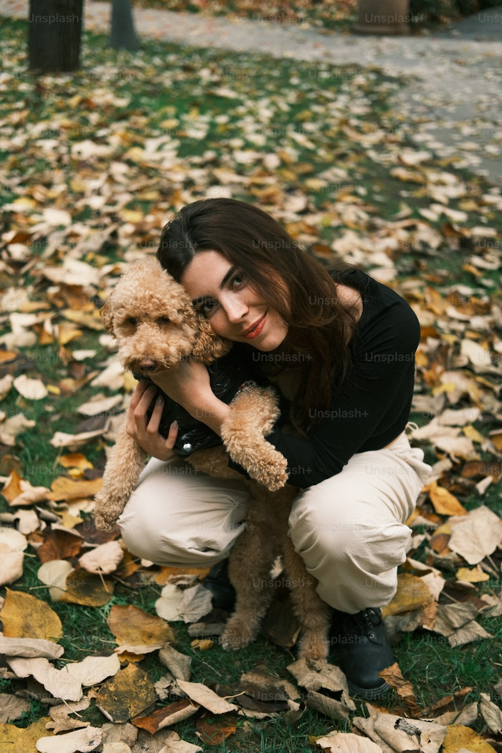 a woman kneeling down holding a dog in her lap