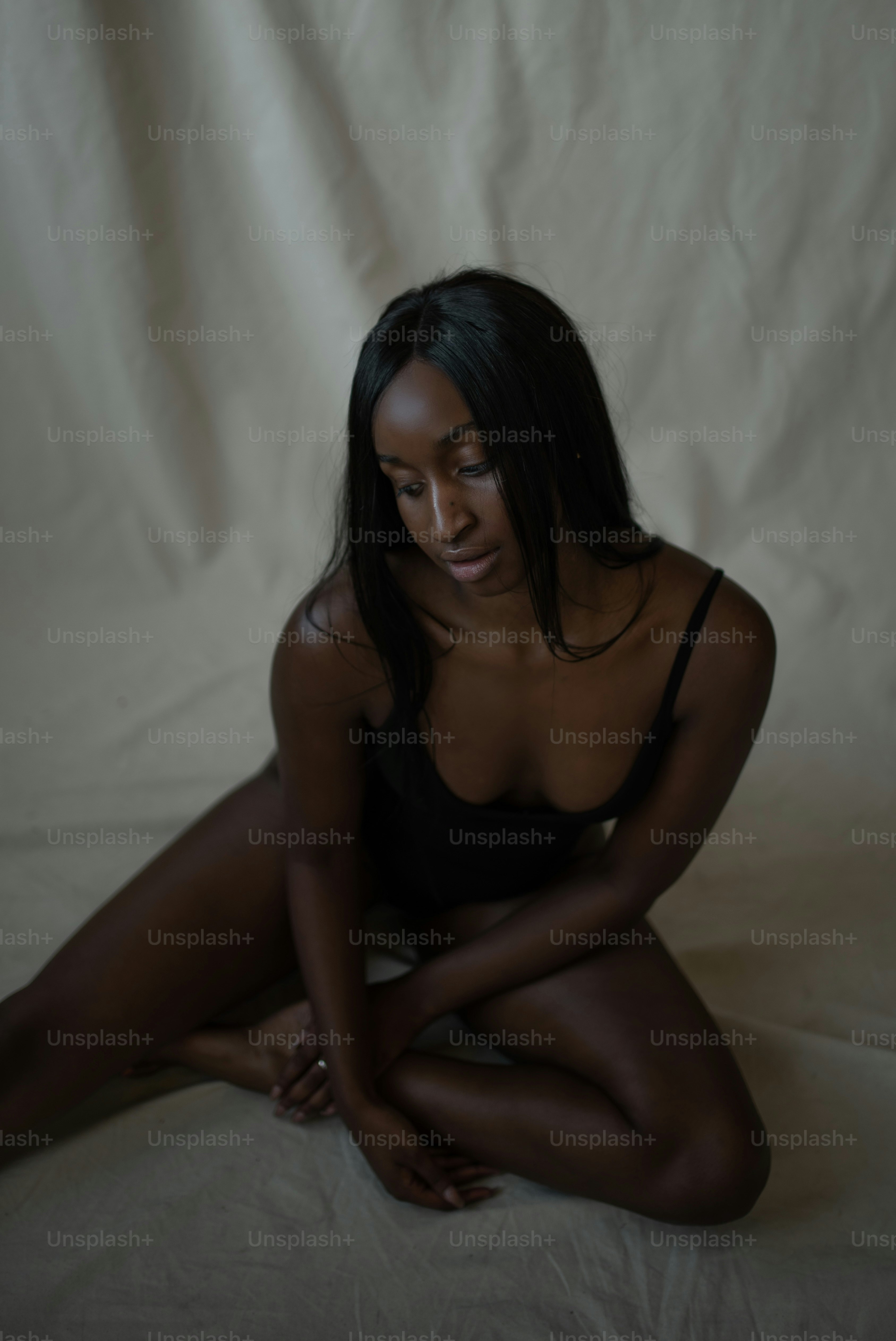 a woman in a black bathing suit sitting on a bed