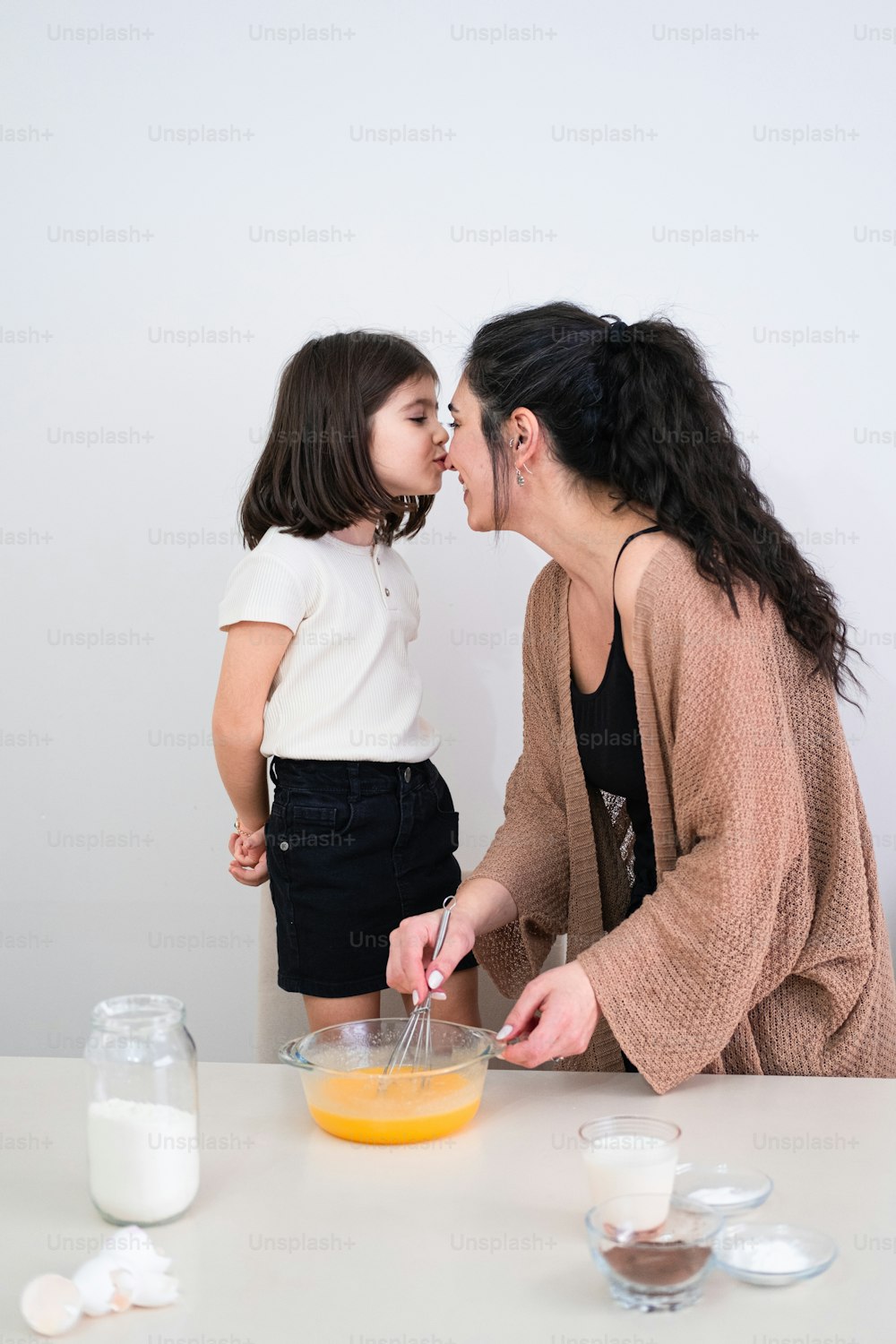 a woman and a little girl standing in front of a table